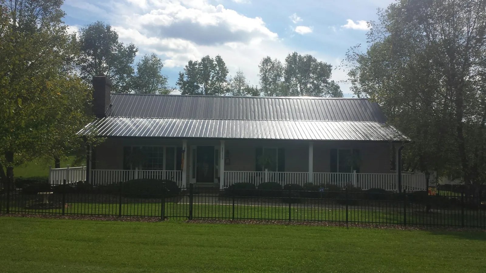 Gray metal roof on a brick ranch with a full width front porch — Gutter Guard Installation work by our crew in Laporte
