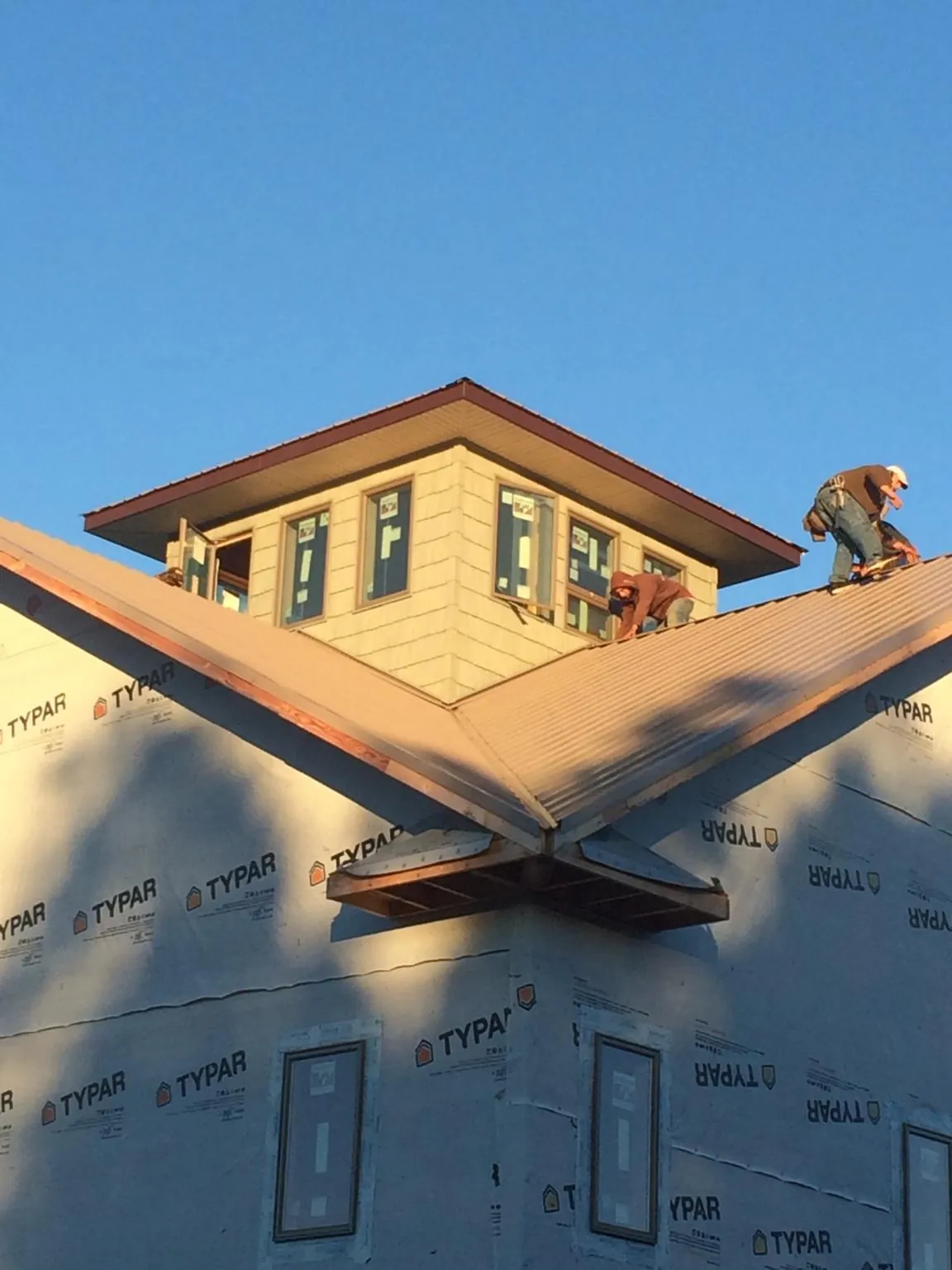 Roofers working around a rooftop cupola on a new metal roof at sunset — Roof Waterproofing in Laporte by Roofing Brothers